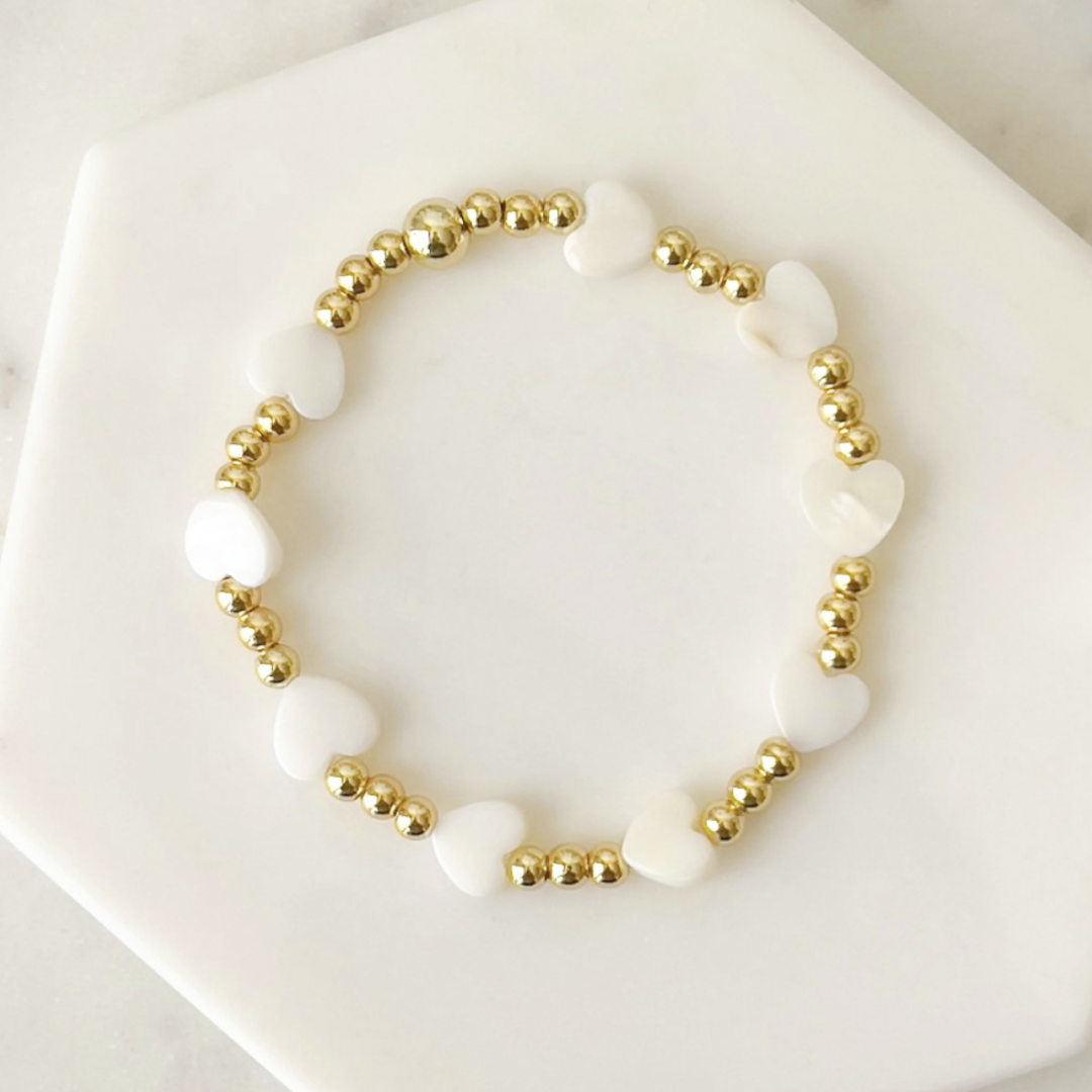 Bracelet with white beads and gold accents on a white surface