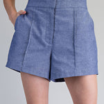Blue denim skirt worn by a person on a gray background