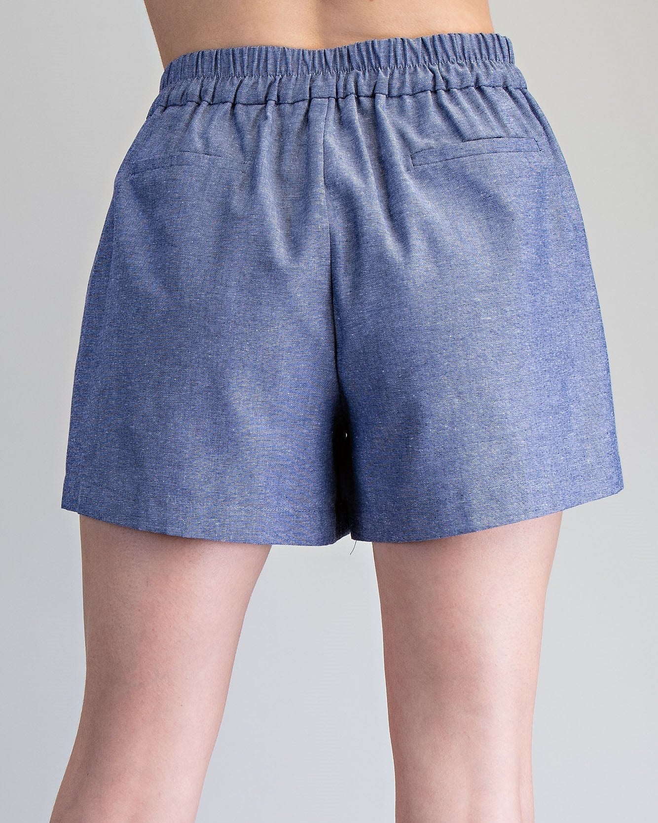 Blue shorts worn by a person on a gray background