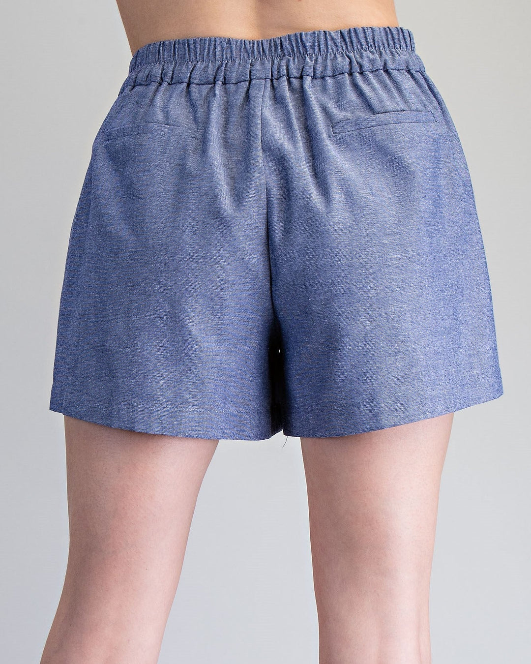 Blue shorts worn by a person on a gray background