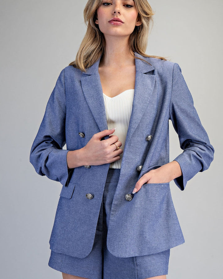 Woman wearing a blue suit with a white top on a gray background