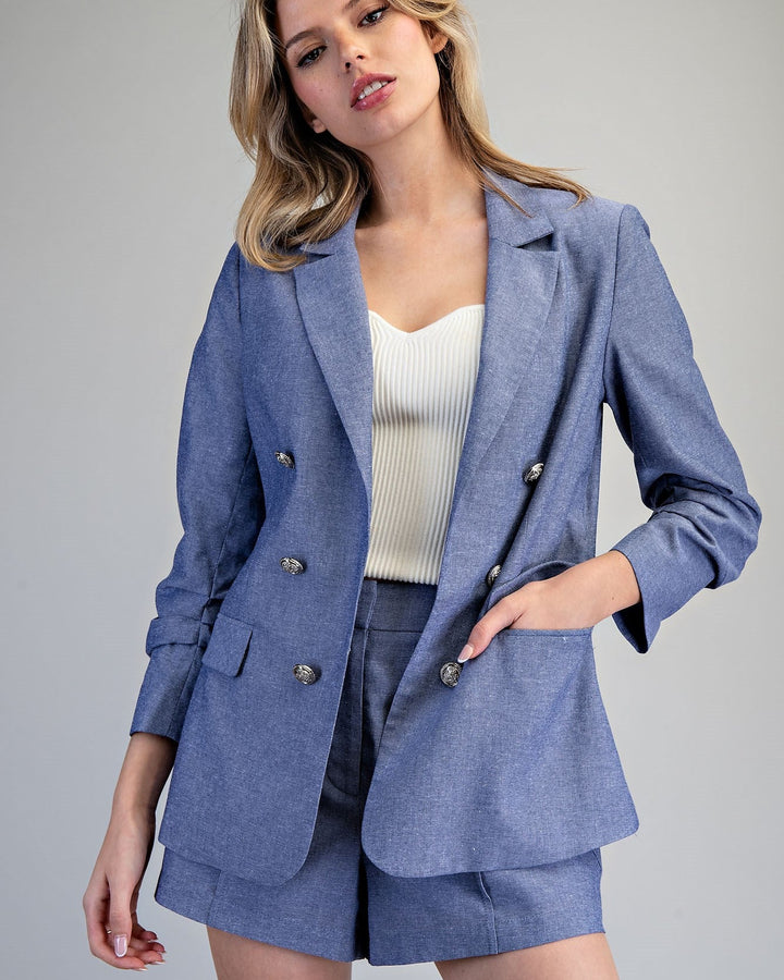 Woman wearing a blue blazer and shorts set on a gray background