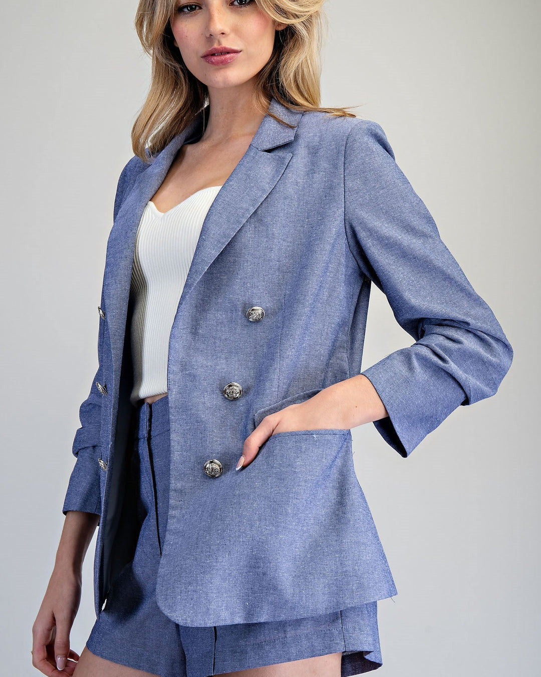 Woman wearing a blue suit with a white top on a gray background