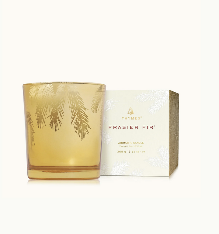 Fir-scented candle with gold leaf design and packaging on a white background