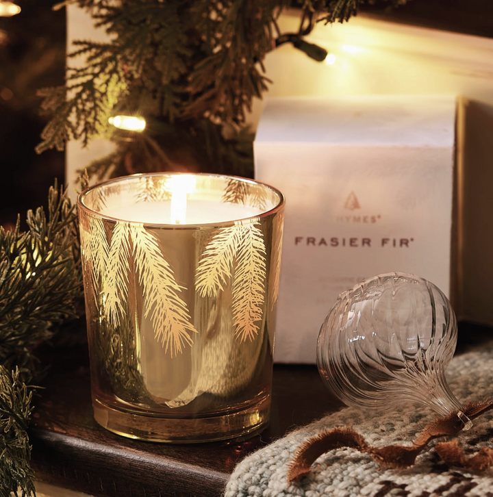 Festive candle with 'Fraser Fir' packaging and decorative elements on a wooden surface.