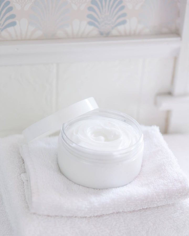 White jar of cream on a white towel with a light blue patterned background
