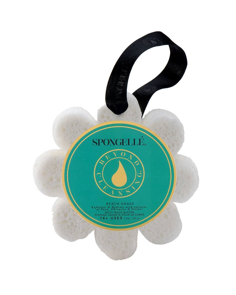 A white floral-shaped Spongelle buffer with a black hanging ribbon, on a green and yellow labeled card, against a white background.