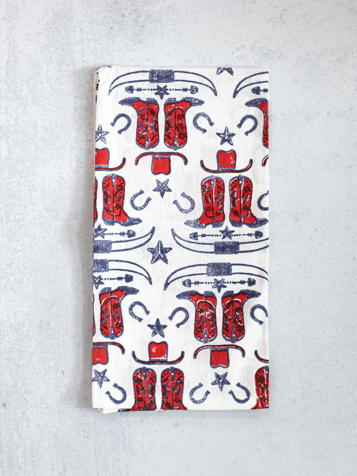 Folded towel with red cowboy boots and blue horseshoes on a white background