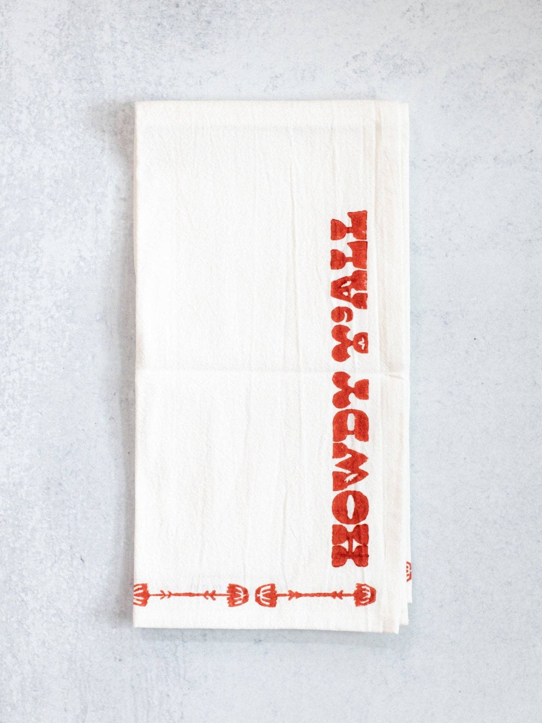 White towel with red text and patterns on a light gray background