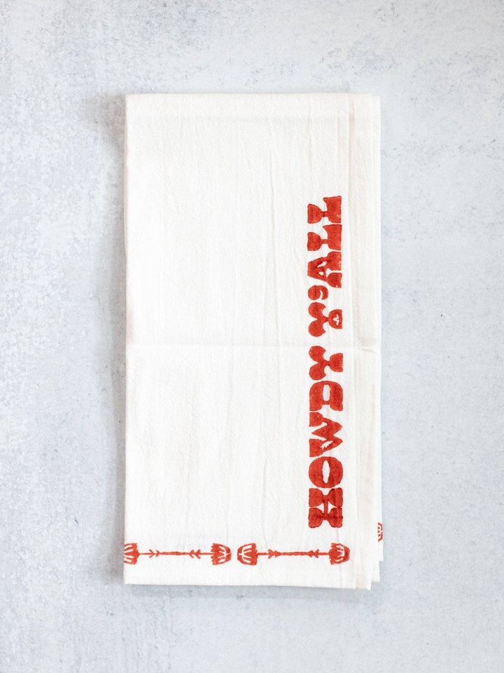 White towel with red text and patterns on a light gray background