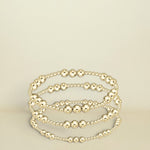 Set of gold beaded bracelets on a white background