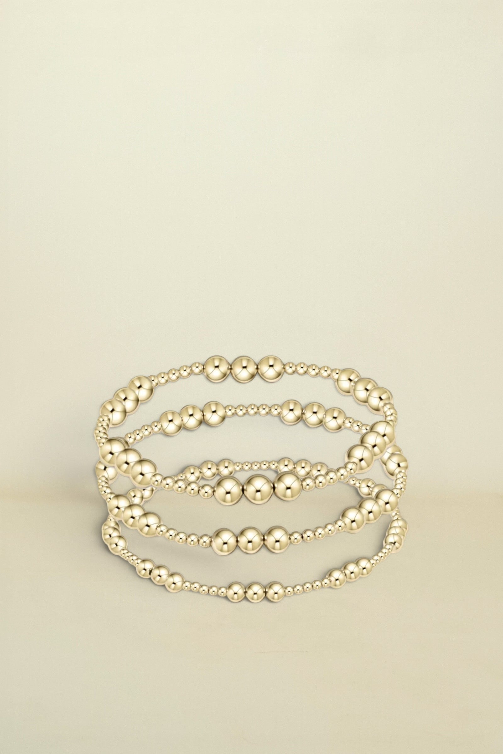 Set of gold beaded bracelets on a white background