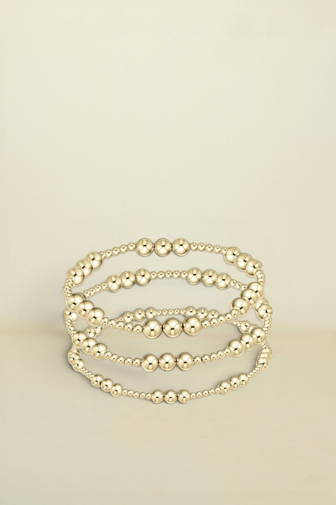 Set of gold beaded bracelets on a white background