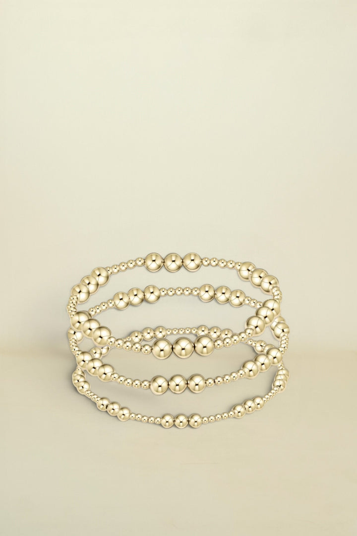 Set of gold beaded bracelets on a white background