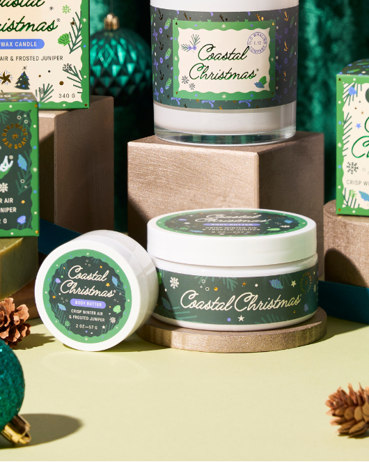 Coastal Christmas-themed candles and packaging with festive decorations on a green background