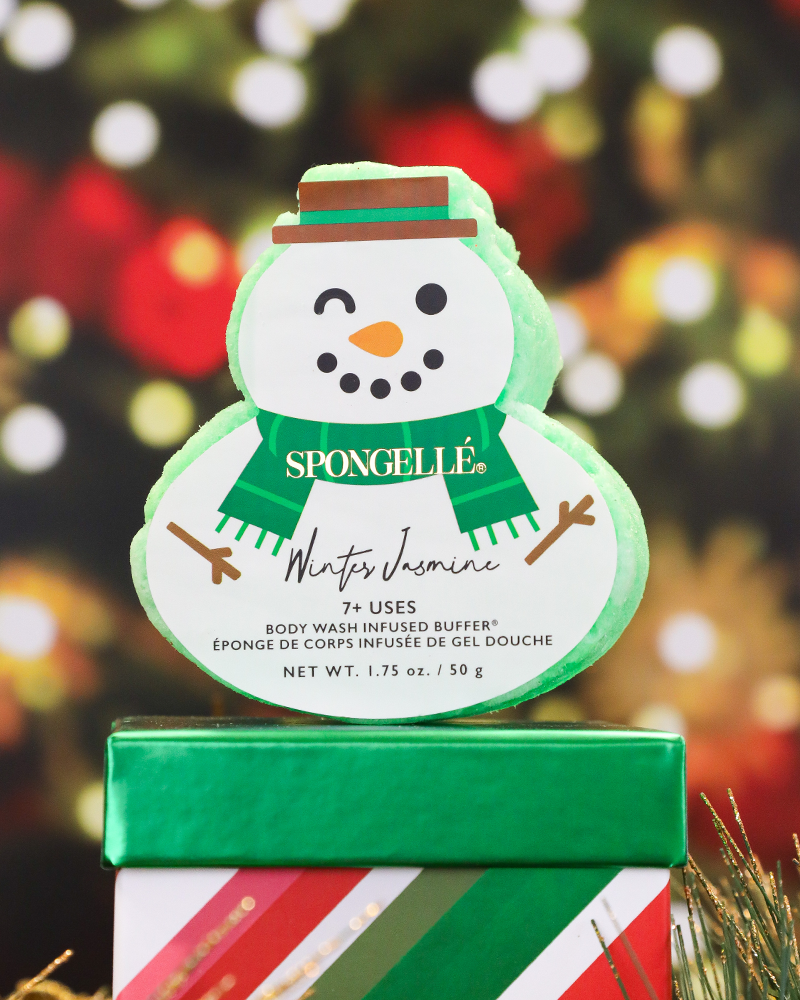 Snowman-shaped product with 'Spongelle' branding on a decorative box against a blurred festive background.