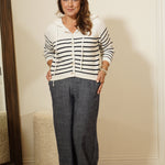 Person wearing a striped shirt and jeans standing in front of a mirror.