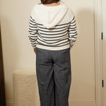 Person wearing a striped shirt and jeans standing in front of a mirror.