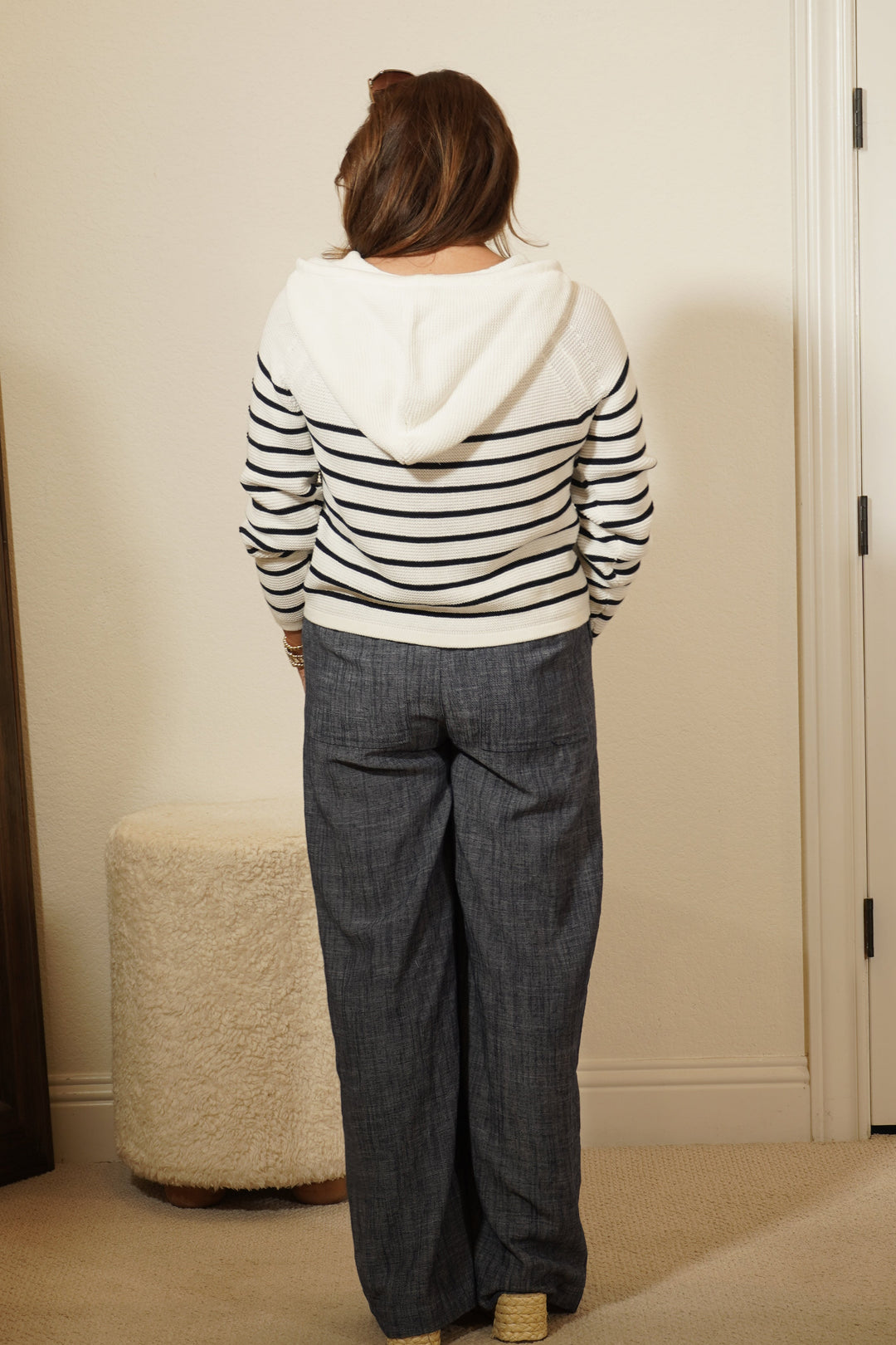 Person wearing a striped shirt and jeans standing in front of a mirror.