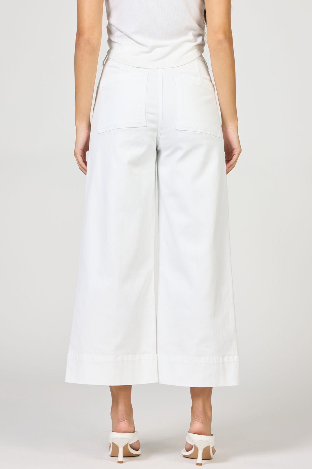 Person wearing white wide-leg pants on a plain background