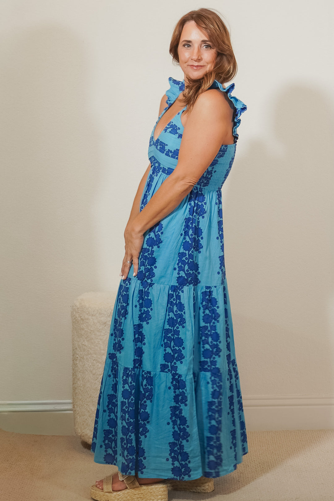 Woman wearing a blue floral dress against a plain background