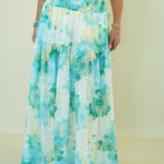 Person wearing a long, floral-patterned skirt with a plain background