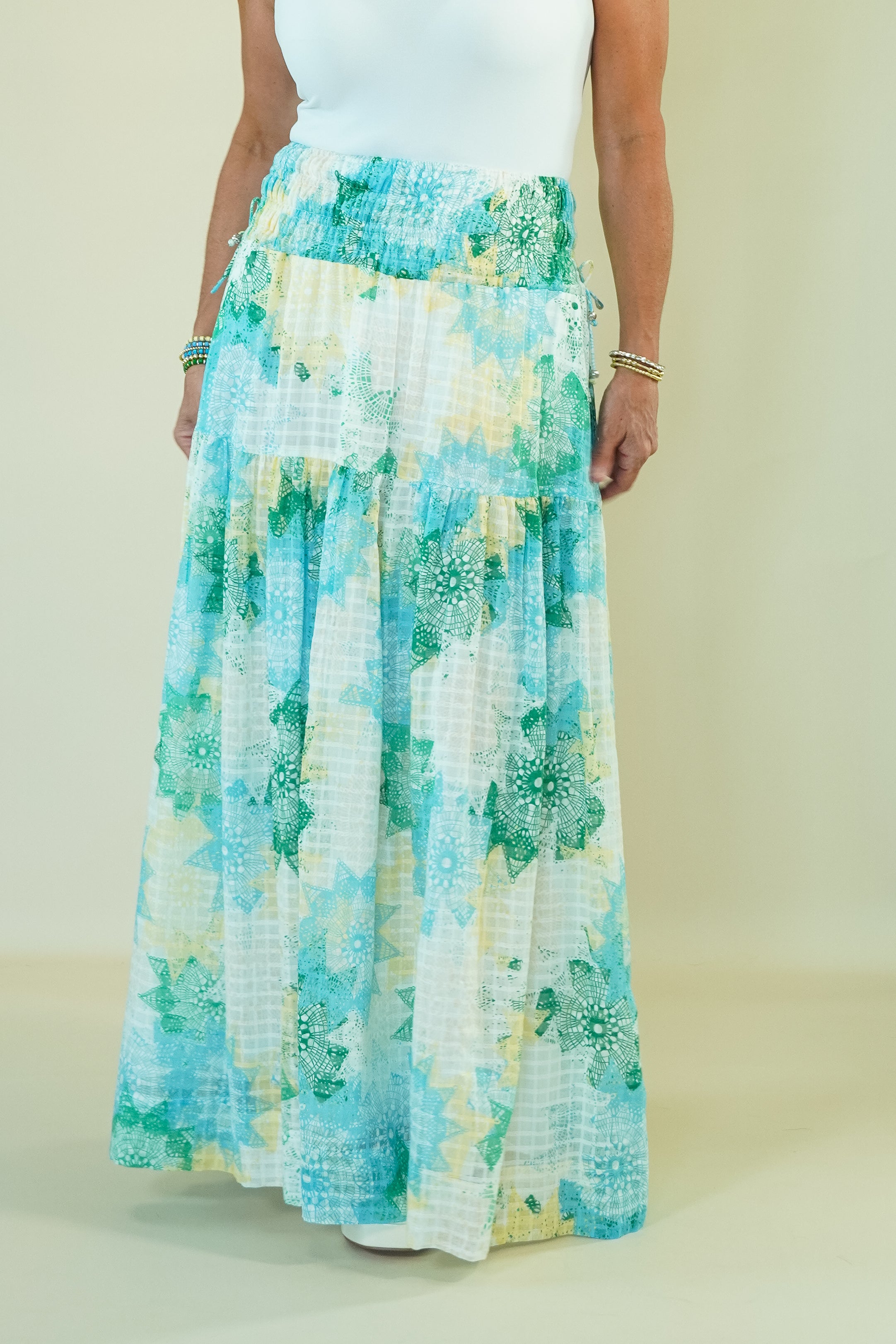 Person wearing a long, floral-patterned skirt with a plain background
