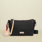 Black leather crossbody bag with a strap and tag on a white background