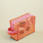 Mesh toiletry bag with pink zipper on a beige background