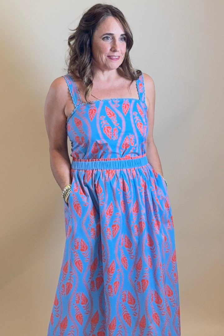 Woman in a blue dress standing in front of a mirror with a light source above.