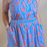 Person wearing a blue dress with a pattern standing in front of a mirror.