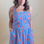 Person wearing a blue dress with red patterns standing in front of a mirror.