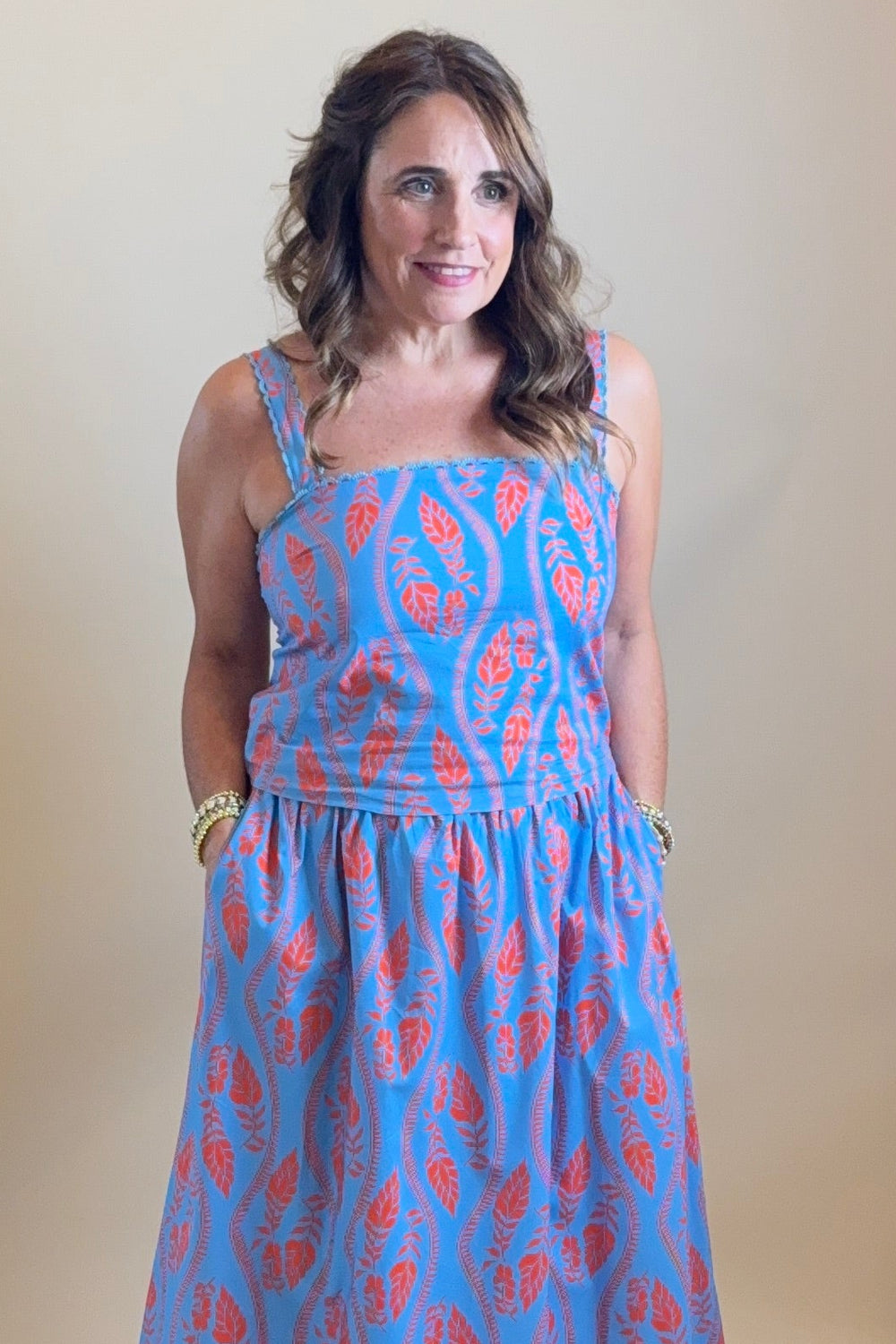 Person wearing a blue dress with red patterns standing in front of a mirror.