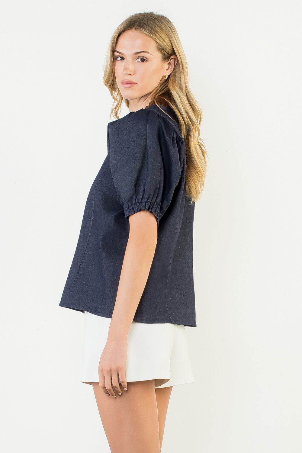 Woman wearing a navy blue top and white shorts on a white background