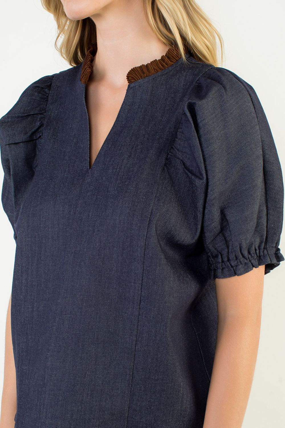 Navy blue blouse with ruffled sleeves worn by a person on a white background