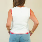 A woman shown from the back wearing a white sleeveless knit top with red trim and light blue denim shorts against a plain beige background.
