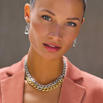 A woman wearing gold-colored pave link post drop earrings and a matching necklace.
