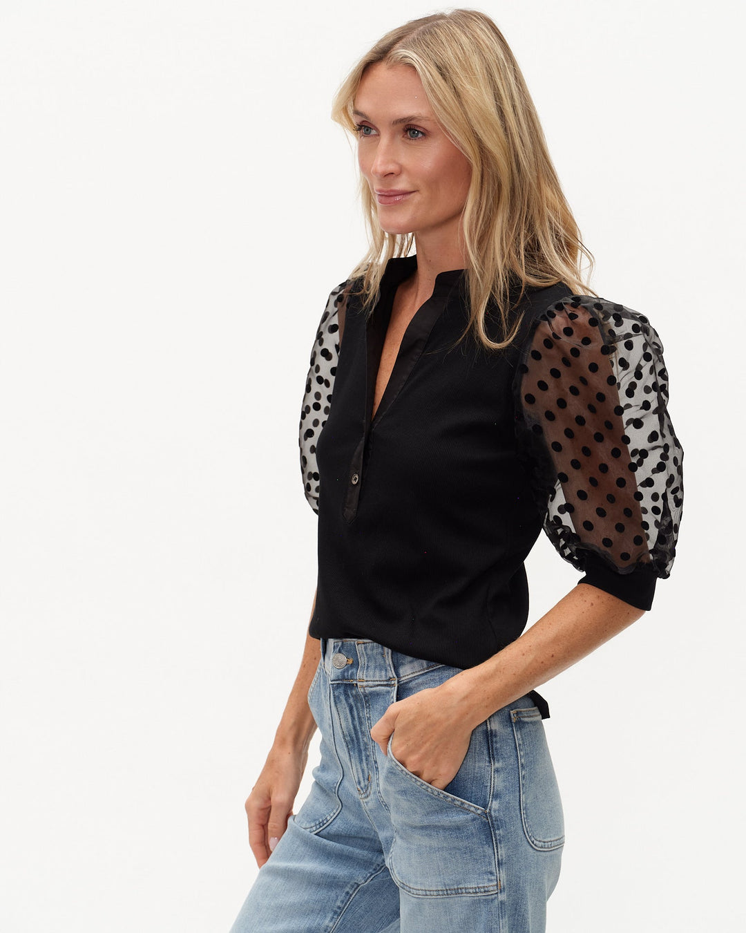 Woman wearing a black blouse with sheer leopard print sleeves on a white background