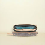 An open zippered pouch or wallet with a distressed gray patterned exterior, a teal blue interior lining, and a light beige interior, shown on a plain cream background.