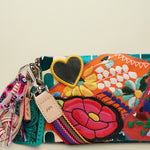 Close up of a colorful embroidered clutch bag with a black heart patch and a leather strap