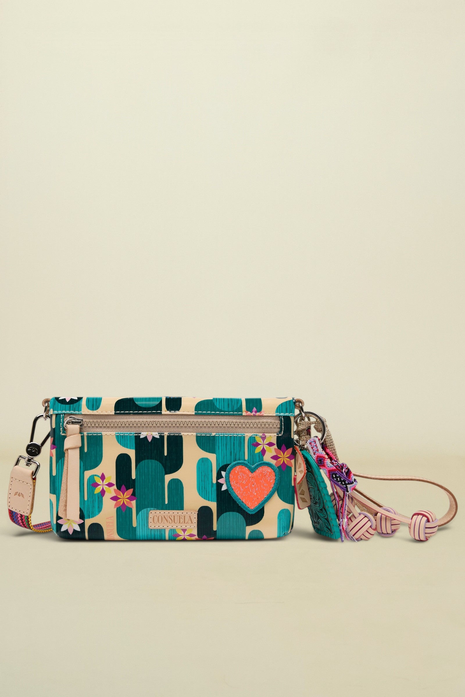 Consuela crossbody bag with a cactus print, a pink heart, and a colorful tassel