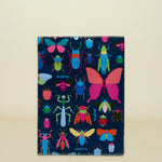 Consuela Gemma Notebook with a dark blue cover and a colorful insect pattern