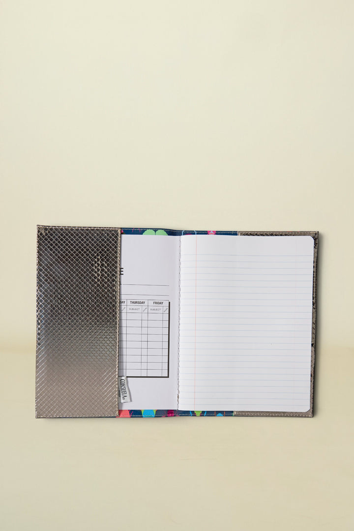 Consuela Gemma Notebook open to a lined page and a schedule page, with a silver textured cover