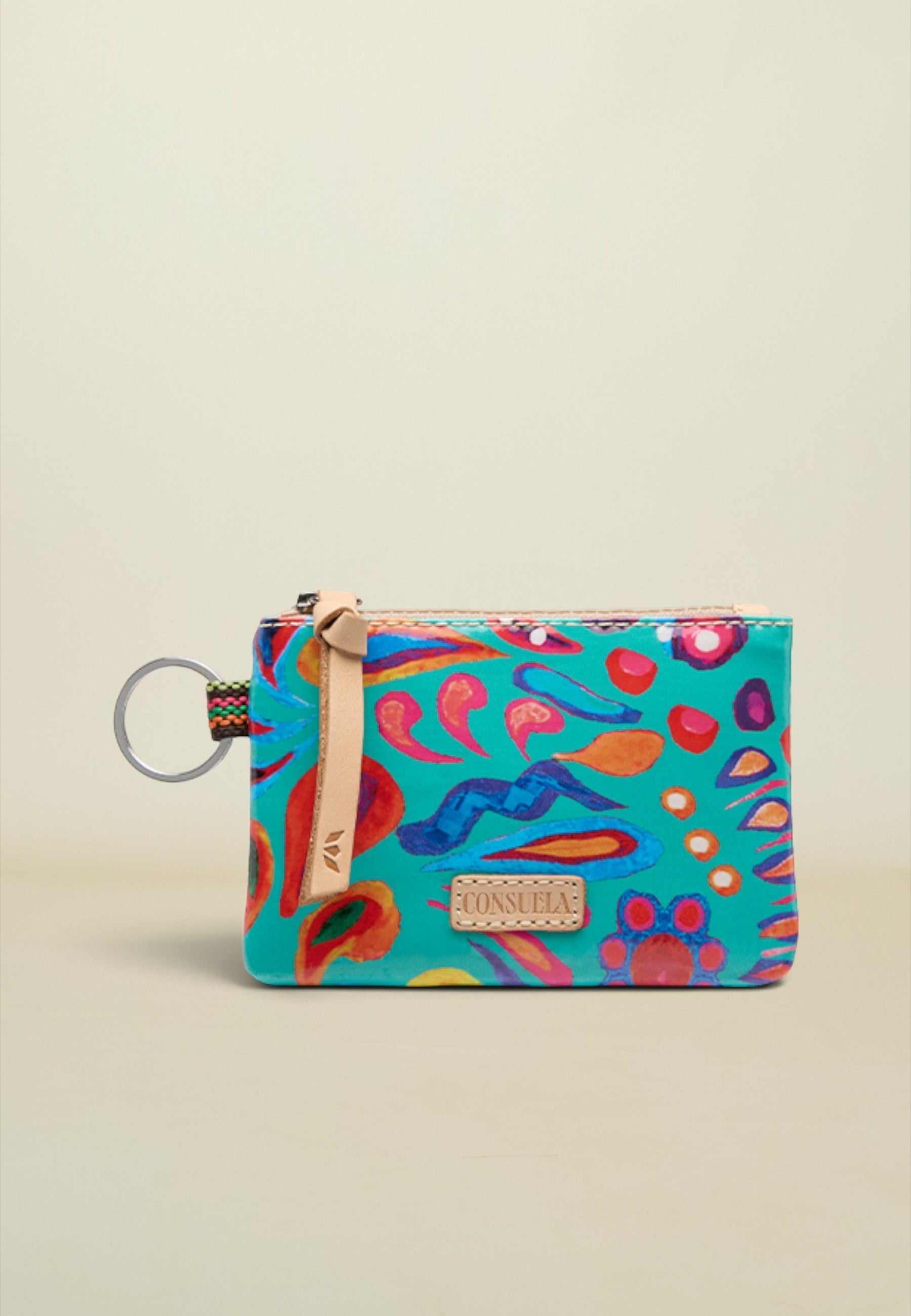 A small zippered pouch with a colorful abstract print on a turquoise background, featuring a beige leather strap and a silver key ring, set against a plain beige background.
