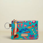 A small zippered pouch with a colorful abstract print in turquoise, pink, orange, and blue, featuring a beige leather strap and a metal key ring on a light beige background.
