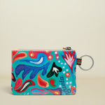 A small zippered pouch with a vibrant multicolor abstract print on a turquoise background, featuring a silver metal key ring attachment.
