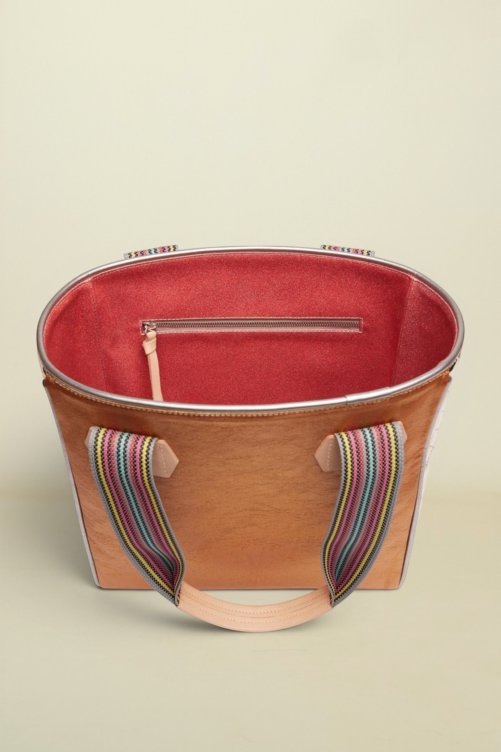 Brown tote bag with colorful handle on a beige background