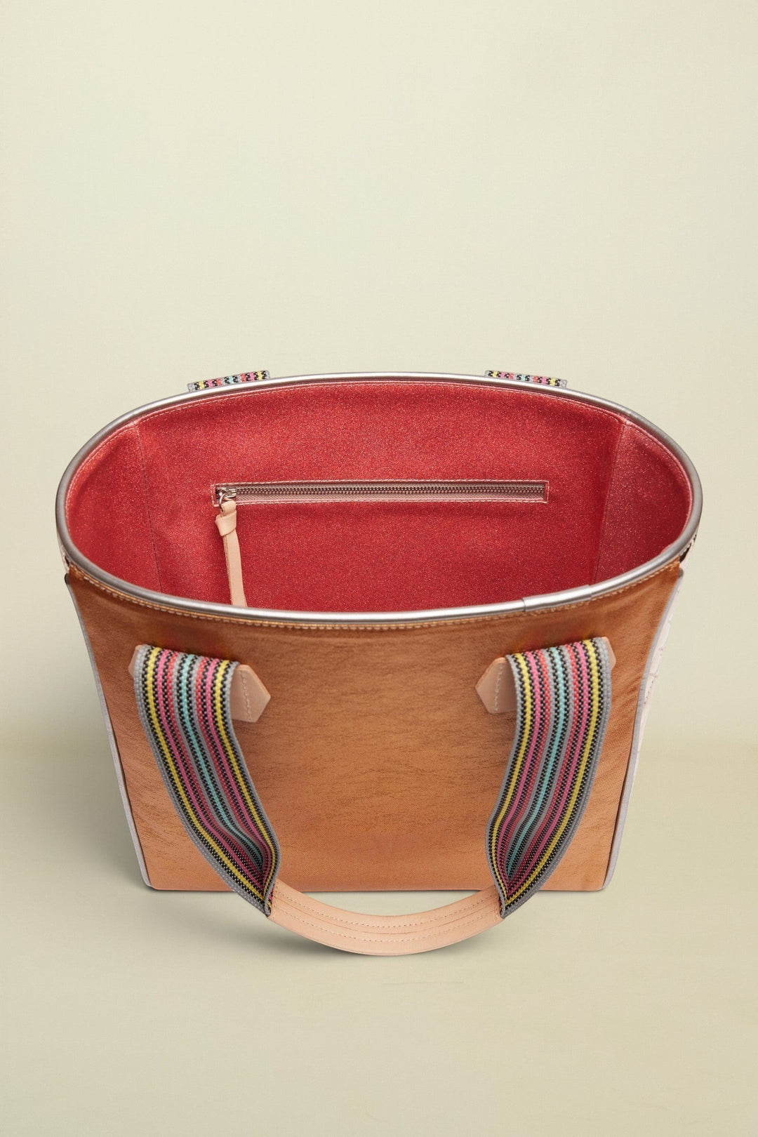 Brown tote bag with colorful handle on a beige background