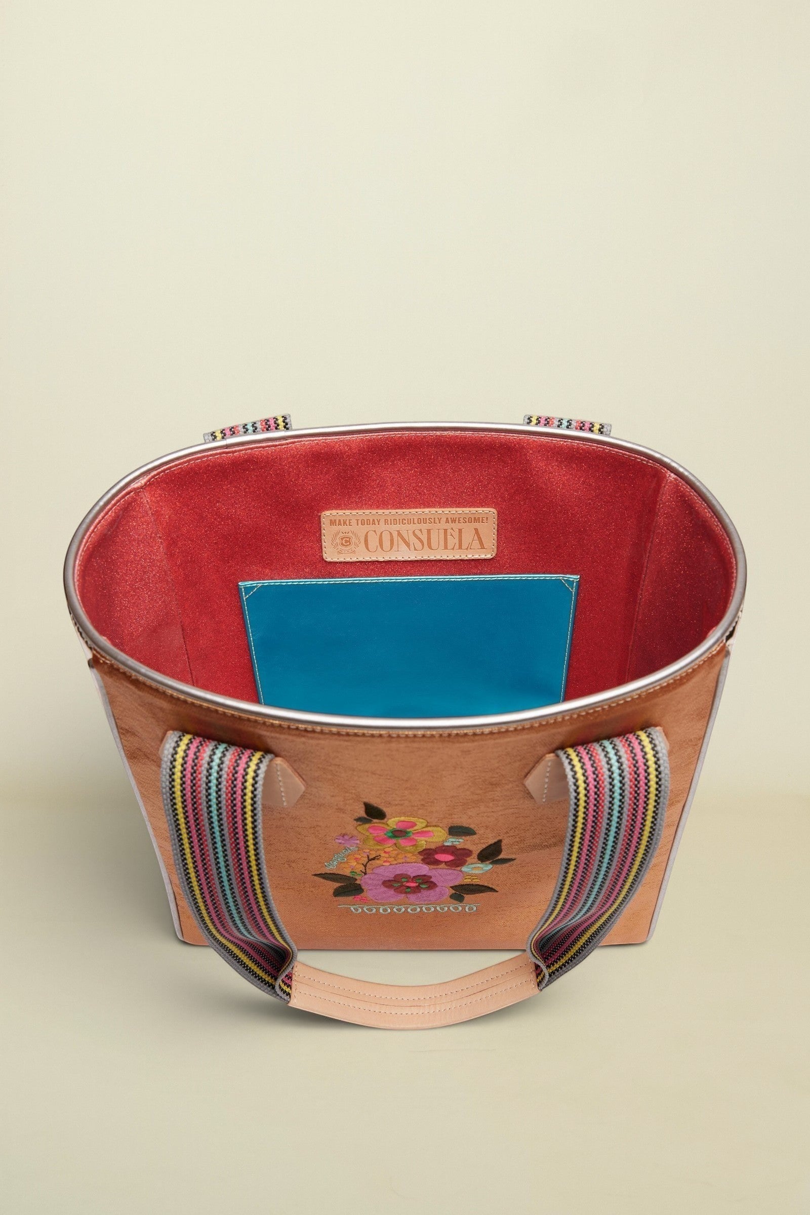Handbag with floral embroidery and colorful handle on a beige background