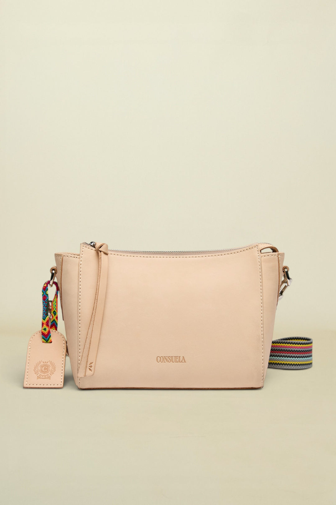 Beige handbag with a colorful strap and tag on a white background